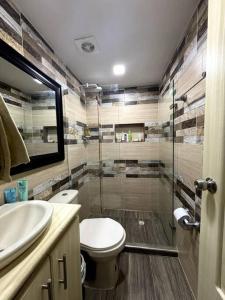 uma casa de banho com um WC e uma cabina de duche em vidro. em Cozy Apt in Coveñas CCampestre em Coveñas