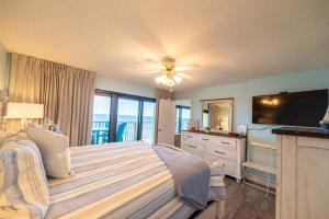 um quarto com uma cama, uma televisão e uma varanda em Commodore 1306 'Dream Come True' em Panama City Beach