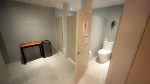 La salle de bains est pourvue de toilettes et d'une petite table. dans l'établissement The Yellow Capsule Hotel Close to Airport, à Cancún