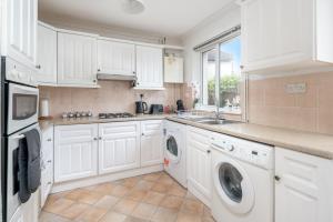 a kitchen with white cabinets and a washer and dryer at Prime Living in Guildford