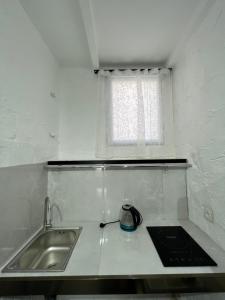 uma pequena cozinha com um lavatório e uma janela em Grozno 6 em Tbilisi