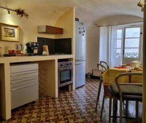 a kitchen with a table and a white refrigerator at Il Bibiribì al Castello in Pieve di Teco