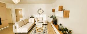 a living room with two white couches and a clock on the wall at La Dolce Vita in Durrës