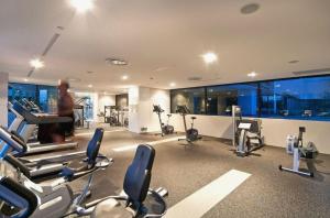 een fitnessruimte met cardio-apparatuur en een man op een piano bij Luxury Oracle Tower 1 Apartment 2Bed 2Bath 1 Car in Gold Coast