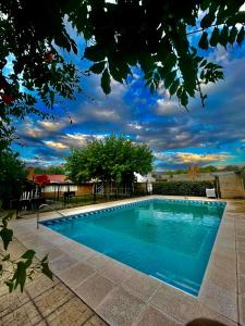 una piscina azul con un cielo nublado en el fondo en Los Nonos en Villa Cura Brochero