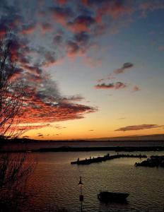a sunset over a body of water with a boat at Atico Praia Cambados in Cambados
