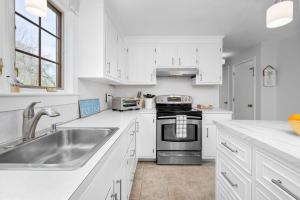a white kitchen with a sink and a stove at 21 Dexter Avenue Sandwich - Creekhaven Cottage in Sandwich