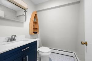a bathroom with a white toilet and a blue cabinet at 21 Dexter Avenue Sandwich - Creekhaven Cottage in Sandwich +25 photos