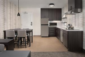 a kitchen with a table and a refrigerator and cabinets at Residence Inn by Marriott Fresno Clovis in Clovis