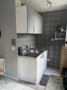 a kitchen with white cabinets and a sink at Studio charmant centre d Aubervilliers in Aubervilliers