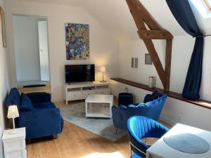 un soggiorno con sedie blu e TV di Maison cosy avec extérieur et piscine partagée a Mespaul