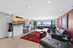 a living room with a leather couch and a television at 3 Story Oceanfront Home with Jacuzzi in Newport Beach on the Sand! in Newport Beach