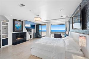 a bedroom with a large bed and a fireplace at 3 Story Oceanfront Home with Jacuzzi in Newport Beach on the Sand! in Newport Beach