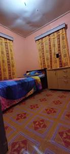 a bedroom with a bed and curtains and a carpet at Kapeta Cabin in Hofoa