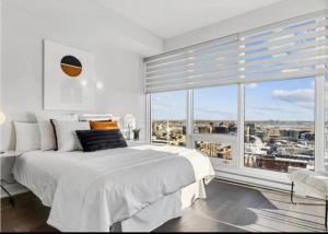 a bedroom with a white bed and a large window at Amazing city view - Penthouse - Pool & Spa - Downtown Montreal in Montreal