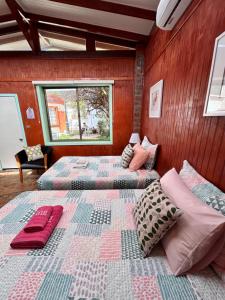 two beds in a room with wooden walls at alojamiento Lof tüng in Los Vilos