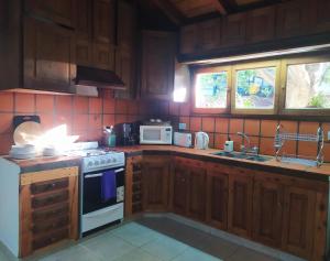 cocina con armarios de madera y horno con fogones en La casita de Maichu en San Martín de los Andes