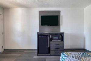 a room with a microwave and a tv on a wall at Motel 6 Lake Charles, LA in Lake Charles