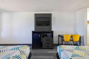 a living room with a tv and two yellow chairs at Motel 6 Lake Charles, LA in Lake Charles