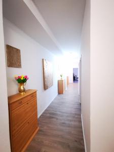 a hallway with a dresser with a vase of flowers on it at Schwert Ferienwohnung Unterkunft Verden in Verden
