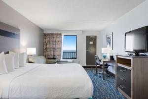 a hotel room with a bed and a flat screen tv at Best Western Plus Holiday Sands Inn & Suites in Norfolk