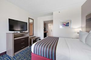 a hotel room with a bed and a flat screen tv at Best Western Plus Holiday Sands Inn & Suites in Norfolk
