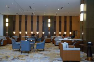 Best Western Plus Danat Almansak Hotel في أبها: مطعم يوجد به كراسي وطاولات في لوبي الفندق