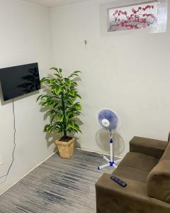 uma sala de estar com um sofá, uma ventoinha e uma planta em Casa Rute - Conforto em primeiro lugar! em Fortaleza