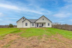 a white house on top of a grassy hill at Modern Sadieville Home with Yard and Gas Grill! in Corinth