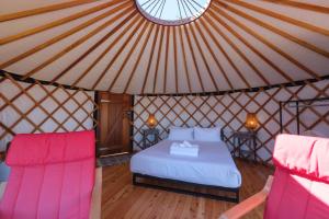 a bedroom in a yurt with a bed and two chairs at Awaawa Yurts - Papa Yurt in Palm Beach