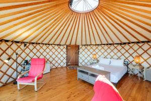 1 dormitorio en una yurta con 1 cama y 2 sillas en Awaawa - Rangi Yurt en Palm Beach
