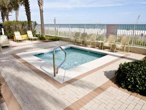 a swimming pool with chairs and the ocean in the background at Pelican Pointe 504 in Orange Beach