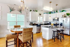 a kitchen with white cabinets and a table and chairs at Surf Station in Carolina Beach