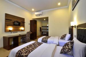 a hotel room with two beds and a desk at Segara Anak Hotel in Kuta Lombok