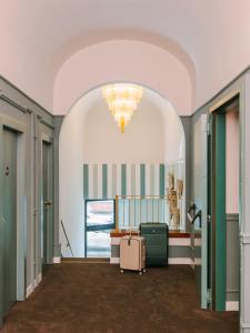 a hallway with a room with a suitcase and a chandelier at The Sonetto powered by Sonder in Florence