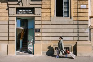a woman walking in front of a building at The Sonetto powered by Sonder in Florence