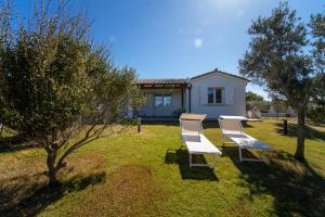 a group of chairs sitting on the grass in front of a house at Residence Isola dei Mori in SantʼAntìoco