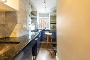 a kitchen with blue cabinets and a stool at Westminster Charm with Roof Terrace in London
