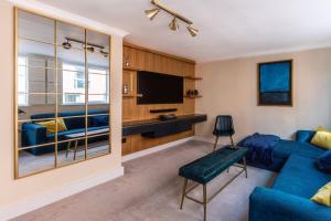 a living room with a blue couch and a tv at Westminster Charm with Roof Terrace in London
