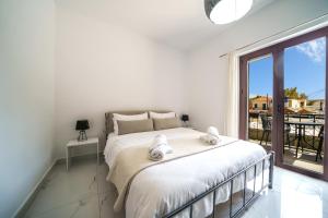 ゲオルギオポリスにあるDimitra & Deslina Luxury Αpartmentsの白いベッドルーム(ベッド1台、大きな窓付)