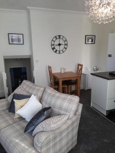 a living room with a couch and a clock on the wall at Beachmount Holiday Apartments in Colwyn Bay