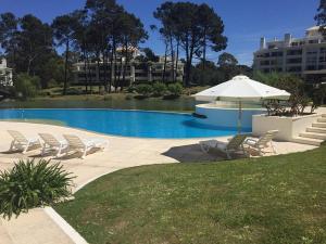 a swimming pool with chairs and an umbrella at Green Park Punta del Este in Punta del Este