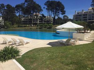 a swimming pool with chairs and an umbrella at Green Park Punta del Este - Full Amenities in Punta del Este