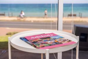 a magazine sitting on top of a white chair at Brighton Beachfront Sanctuary - Retro Coastal Charm in Brighton