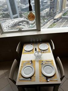 a table with plates and utensils on it with a window at Dubai Entire Serviced Room Unit Excellence in Dubai
