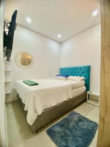 a bedroom with a bed with a blue headboard and a mirror at Apartaestudio Rodadero Sur RW TOWER Piscina in Gaira