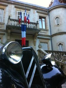 ein schwarzes Auto, das vor einem Gebäude mit Flaggen parkt in der Unterkunft Le Château De Conde En Barrois in Condé-en-Barrois