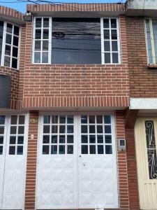 uma casa de tijolos com duas portas de garagem brancas em Hermosa casa con gran ubicación em Bogotá