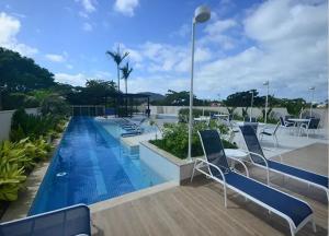 ein Swimmingpool mit Stühlen und Tischen auf einem Gebäude in der Unterkunft Panoramique 180 - Vista Praia in Guarujá