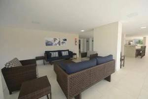 ein Wohnzimmer mit Sofas, Stühlen und einem Tisch in der Unterkunft Panoramique 180 - Vista Praia in Guarujá